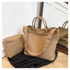 Detail of khaki canvas tote bag set with matching small zipper pouch on black blazer