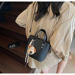 Detail of black lychee grain mini tote with cute cartoon dog pendant and silver hardware
