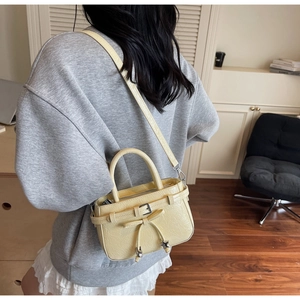 Detail of cream pleated leather bucket bag with star charms and bow on model's shoulder