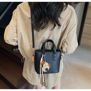 Detail of black lychee leather bucket bag with puppy charm and twilly scarf decoration
