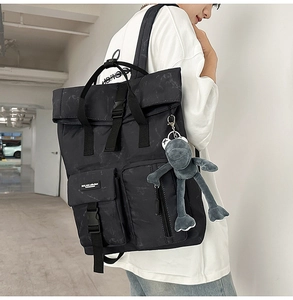 Side view of a large black backpack with marble pattern and a cute plush frog keychain