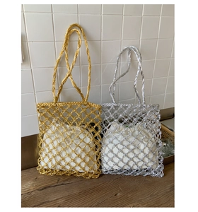 Detail of woven mesh tote bags in gold and silver with drawstring liners on a wooden table