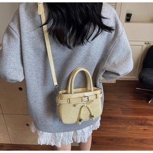 Detail of light yellow leather handbag with bow and star charm worn by a model