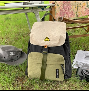 Outdoor shot of a multi-color waterproof nylon backpack with a yellow smiley embroidery
