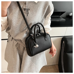 Detail of black lychee leather bowling bag with silver whale charm and thin strap