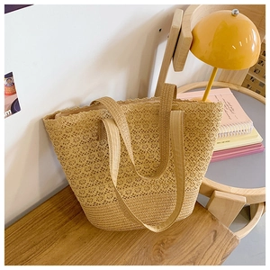 Detail of woven straw tote bag featuring intricate hollow lace patterns and sturdy bottom