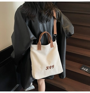 Detail of canvas tote bag with brown XQY embroidery and adjustable shoulder strap