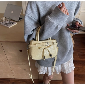 Detail of beige bow handbag showing ruched texture and star charm in a lifestyle setting
