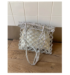 Close-up of metallic silver woven tote bag with hollow mesh and drawstring inner pouch