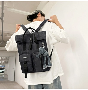 Side view of marble print backpack featuring roll-top buckle and plush frog charm accessory