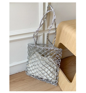 Detail of silver woven mesh handbag with a white drawstring inner pouch on wooden chair