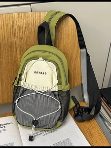 Sac bandoulière en nylon vert et blanc cassé avec poche filet et cordon sur chaise bois