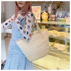 Detailed texture of beige lace woven tote bag with durable reinforced bottom