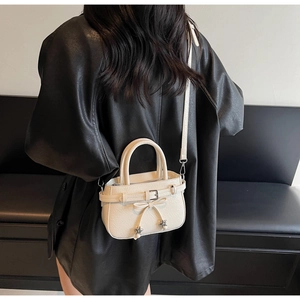 Detail of cream crossbody bucket bag with bow knot and silver star charm on leather