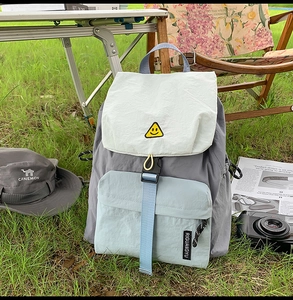 Detailed close-up of a color-block nylon travel backpack set on a green outdoor lawn
