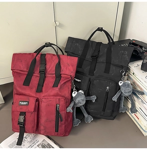 Detail of roll-top backpacks with marble texture and plush frog charm in red and black