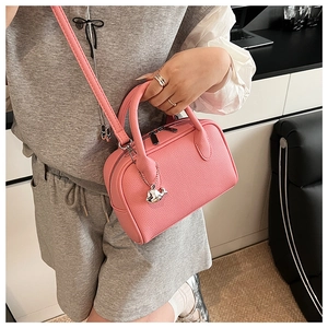 Pink pebbled leather Boston bag detail with silver whale charm and thin shoulder strap