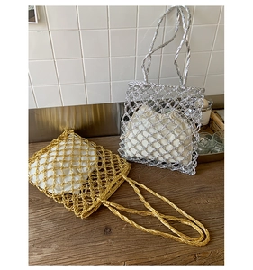 Close-up of gold and silver mesh tote bags with woven rope handles on a wooden table