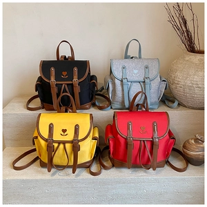 Detailed close-up showing vintage canvas backpacks in four colors on stone steps