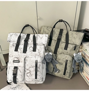 Detail of waterproof roll-top backpacks with marble print and plush frog accessory