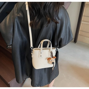 Mini crossbody bucket bag with litchi grain texture and plush dog pendant on a model