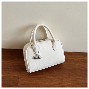 Detailed side view of white litchi pattern bowling bag with silver whale charm