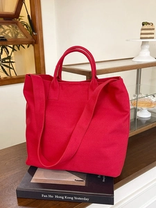 Red canvas tote bag with adjustable strap on photography books in a cozy setting