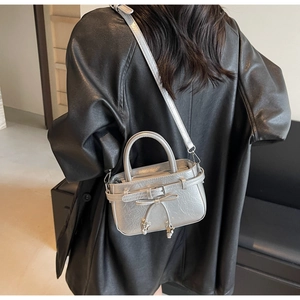 Silver metallic bucket bag with bow detail and fringe tassel on black leather coat