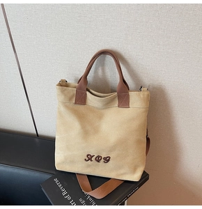 Detail of khaki canvas tote with XQY embroidery and adjustable crossbody shoulder strap