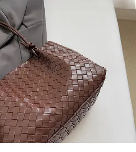 Detailed view of dark brown woven leather texture with knots on a soft shoulder bag