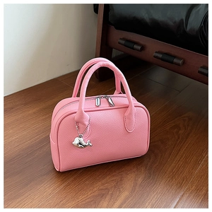 Detail of pink lychee leather bowling bag with silver zipper and dolphin charm