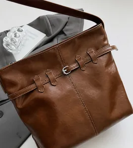 Close-up of brown leather tote bag with buckle detail and refined stitching texture
