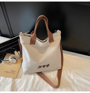 Detailed close-up of a cream canvas tote bag with brown straps on a minimal desk set