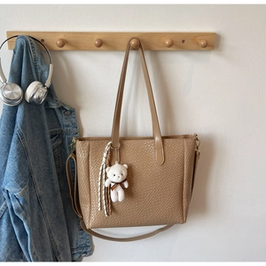 Detail of the woven texture and bear charm on a large light brown commuter tote bag