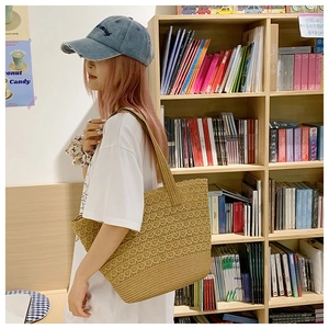 Detailed close-up of khaki woven straw tote bag with crochet hollow and dense weave texture