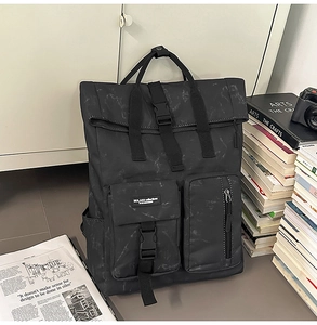 Detail of black marble textured roll-top backpack with adjustable buckles and pockets