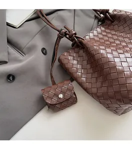 Detail of dark brown woven leather tote with intricate texture and knotted shoulder strap