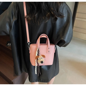 Detail of pink lychee leather bucket bag with Gromit plush pendant and metallic rivets