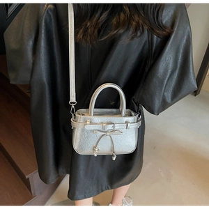 Silver metallic bucket bag with bow detail worn by a model in a black leather coat