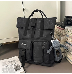Detail of large black marble pattern backpack with roll-top closure and plush toy charm