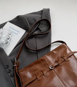 Close-up of vintage brown PU leather shoulder bag with metallic buckle and strap details