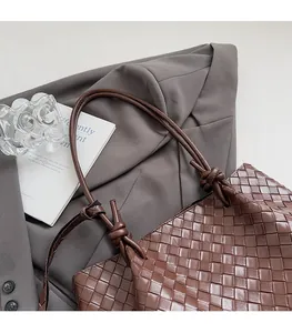 Detail of brown woven leather tote featuring Intrecciato weave and knotted strap design