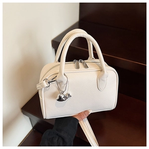Detail of cream bowling bag showing pebbled leather texture and silver whale charm