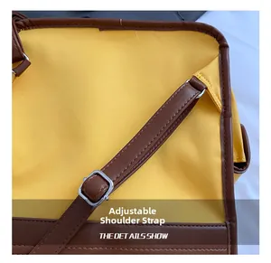 Detail view of the adjustable brown shoulder strap with silver buckle on a yellow backpack