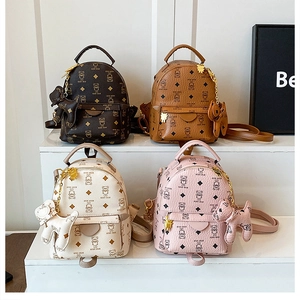 Detail showing various colors of mini leather backpacks with bear prints and charms