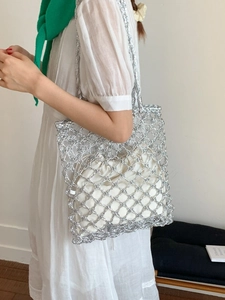 Silver metallic woven tote bag with drawstring lining shown on a model in sunlight