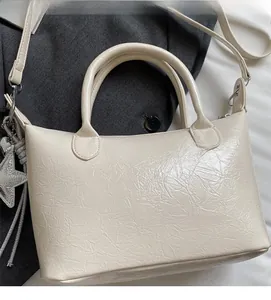 Dettaglio borsa in pelle pieghettata crema con ciondolo a stella e tracolla rimovibile