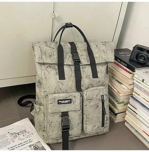 Detail of grey marble texture backpack with roll-top closure and front buckle pockets