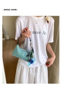 Detail of light blue woven tote bag with cute elephant pendant and metal hardware