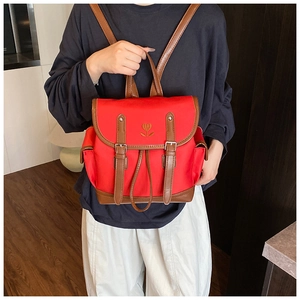 Detail of red nylon backpack featuring brown leather trim and heart embroidery detail